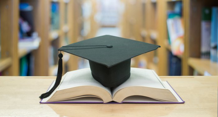 Zertifikate und Weiterbildung – Abschlusskappe auf offenem Buch